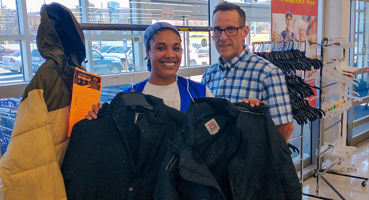 OSJL Front End Supervisor Taja Lanier with loyal OSJL customer Mike Marchetti and some of the 50 Buy-Give-Get coats Mike purchased to benefit the Kingston Rotary Club.