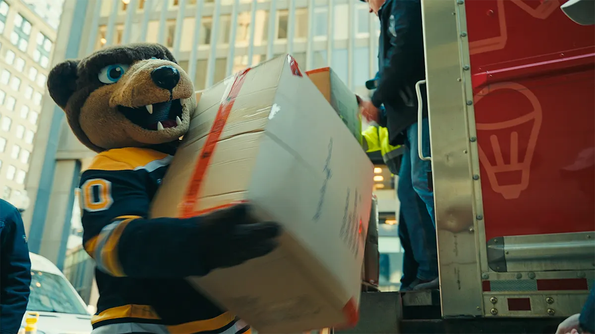 Blades, the Boston Bruins Mascot, helps to unload donated coats.